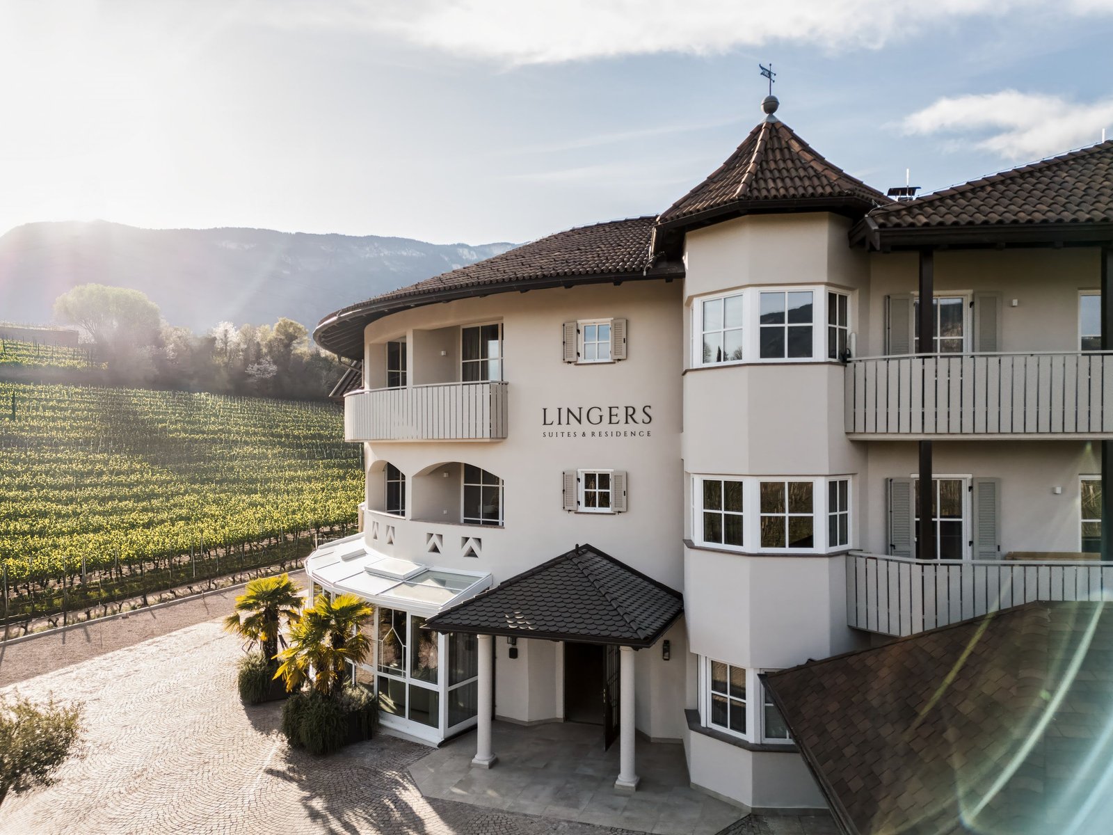 Lingers Suites & Residence vor Weinbergen und Bergen im Gegenlicht, aus der Luft
