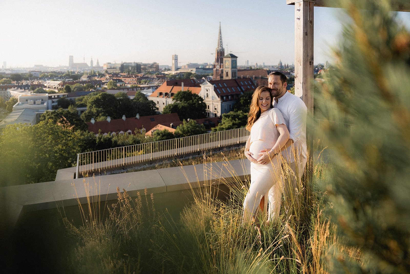 Werdende Eltern im hohen Gras, München im Hintergrund